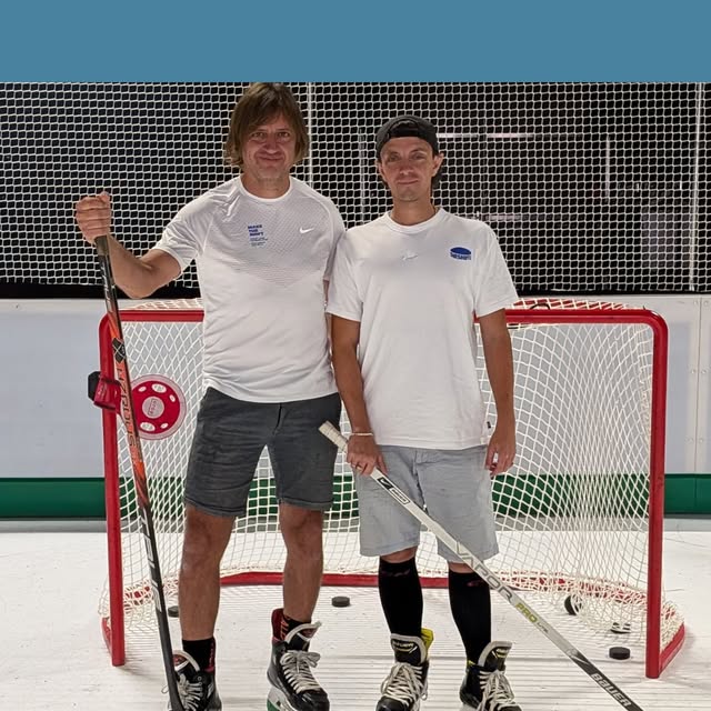 Zwei Mitglieder des TheShift-Teams mit Hockeyschlägern vor dem Tor